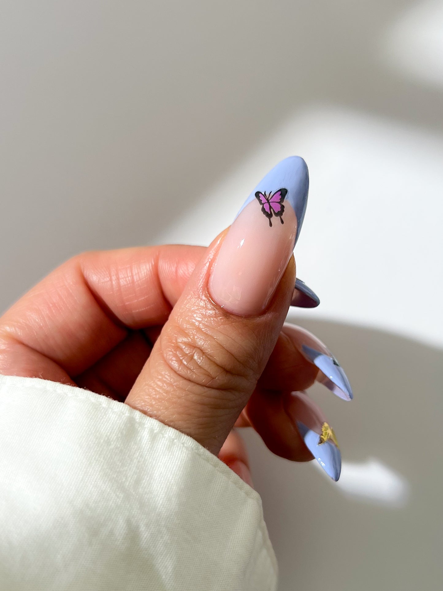 Nail with butterfly sticker against a neutral background