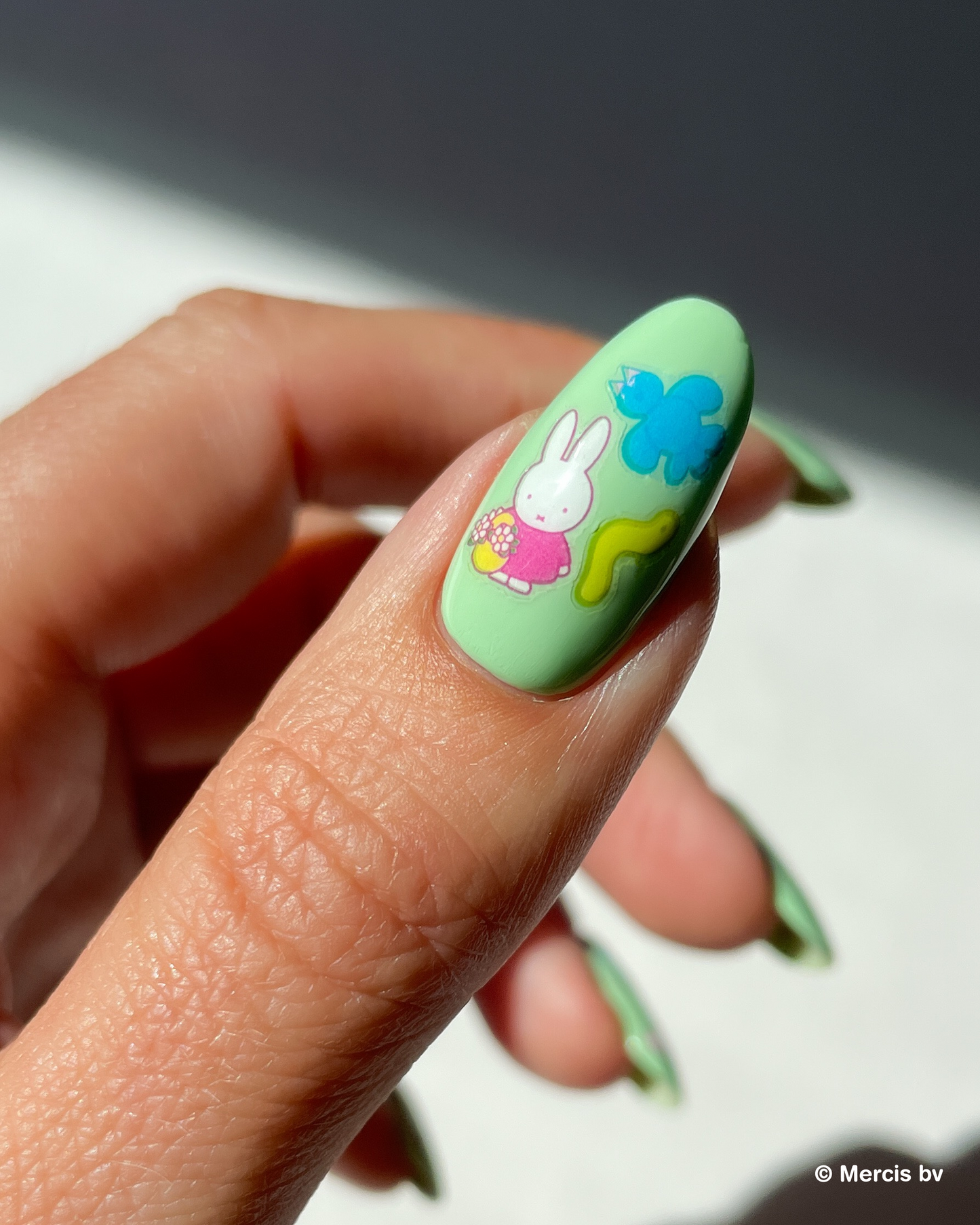 Nail with light green nail polish and miffy nail art stickers