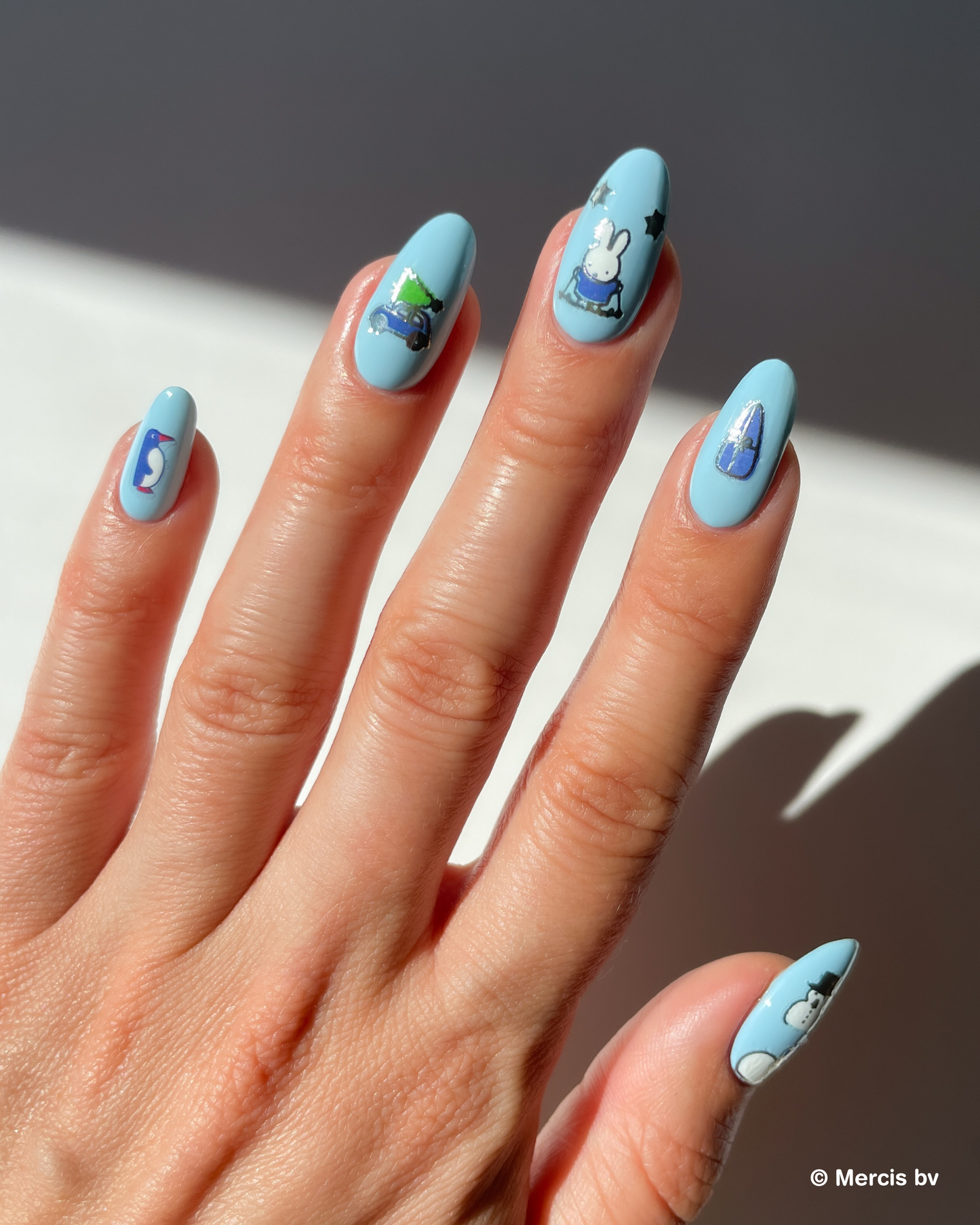 Hand with light blue nails with miffy nail art stickers on a neutral background