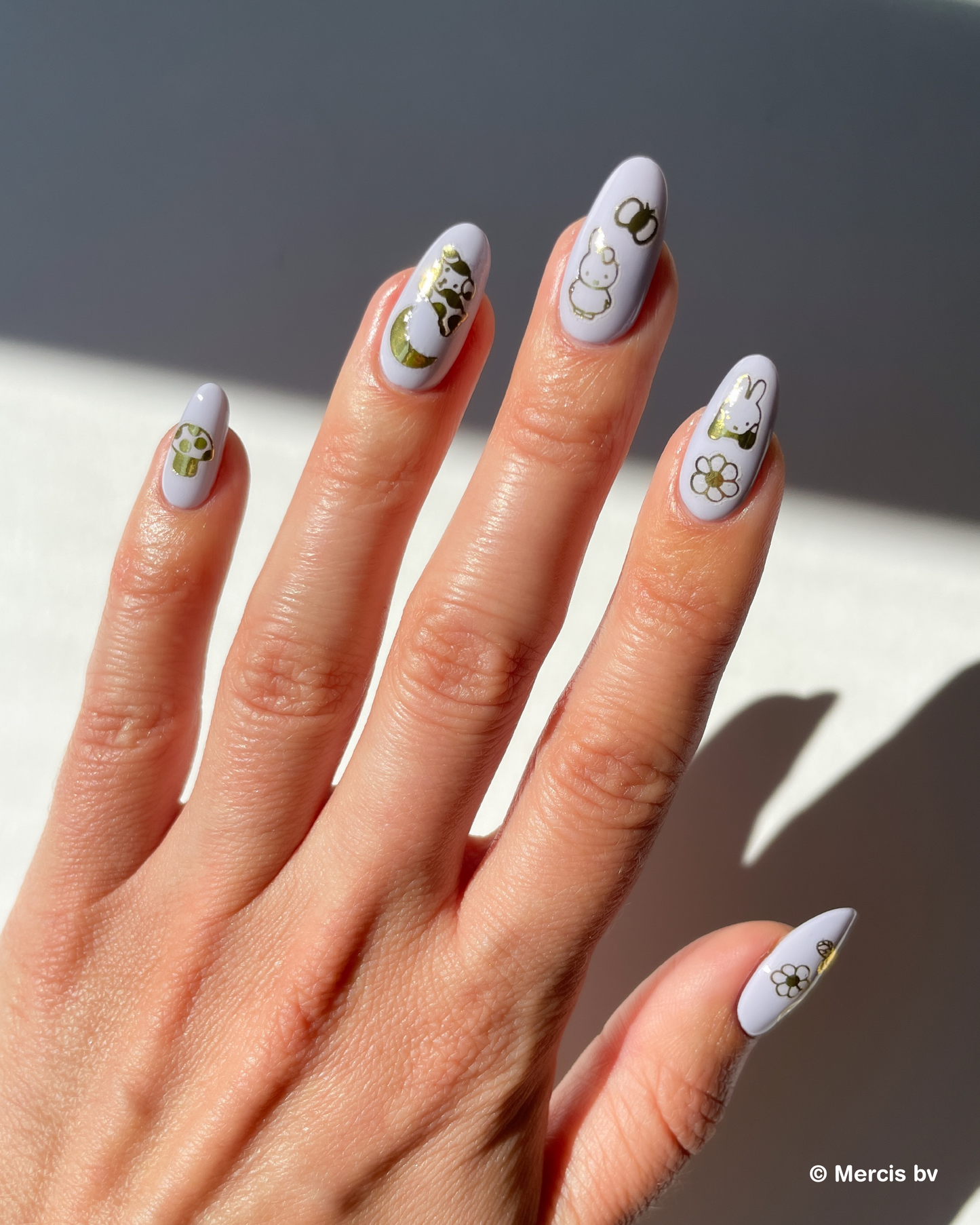 Hand with lavender nail polish and miffy nail art stickers on a neutral background