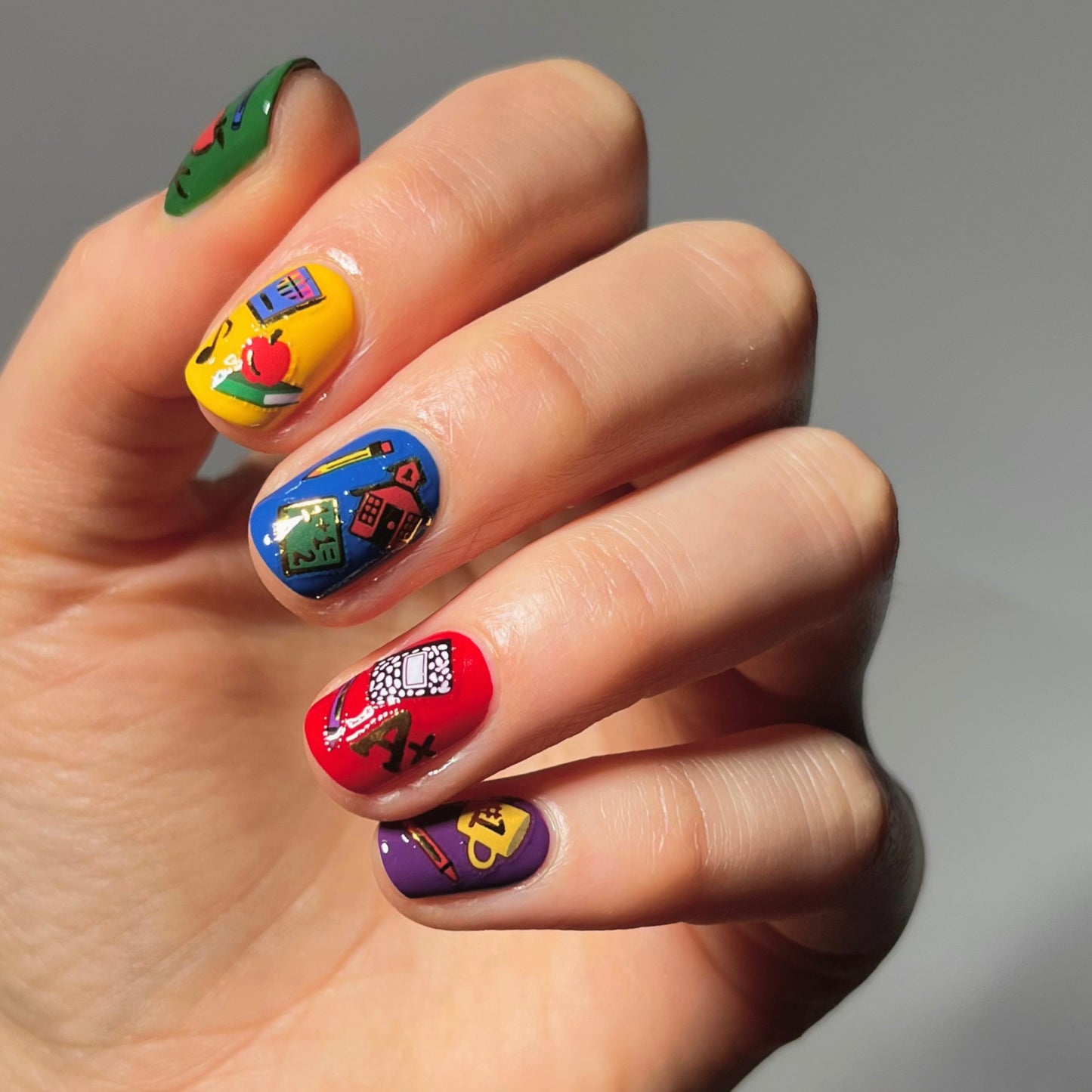 Yellow, blue, red, green, and purple nails with stickers