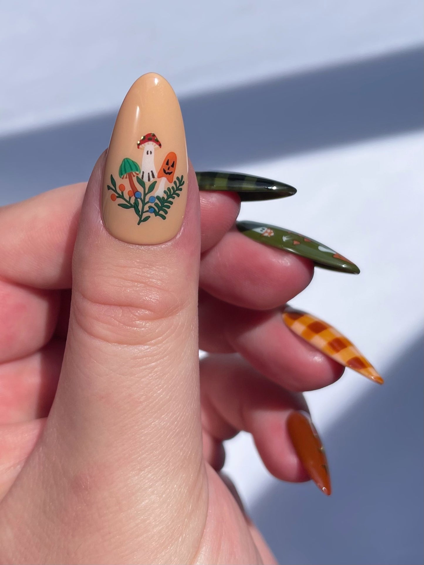 Close up of a thumb nail with beige polish on and stickers from the Toadstool nail art sheet