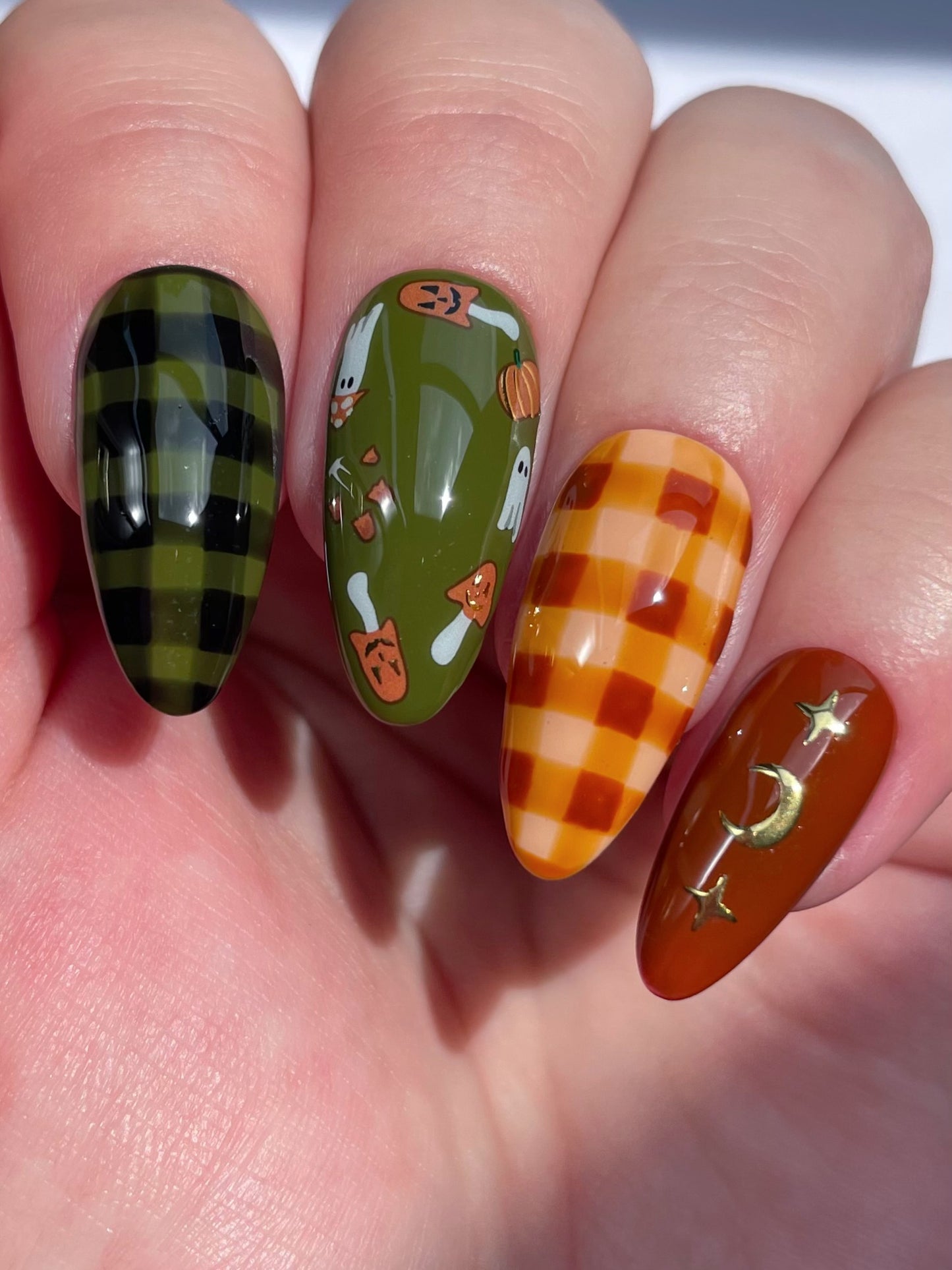 Close up of a hand with green and brown nails featuring stickers from the Toadstool nail art sheet