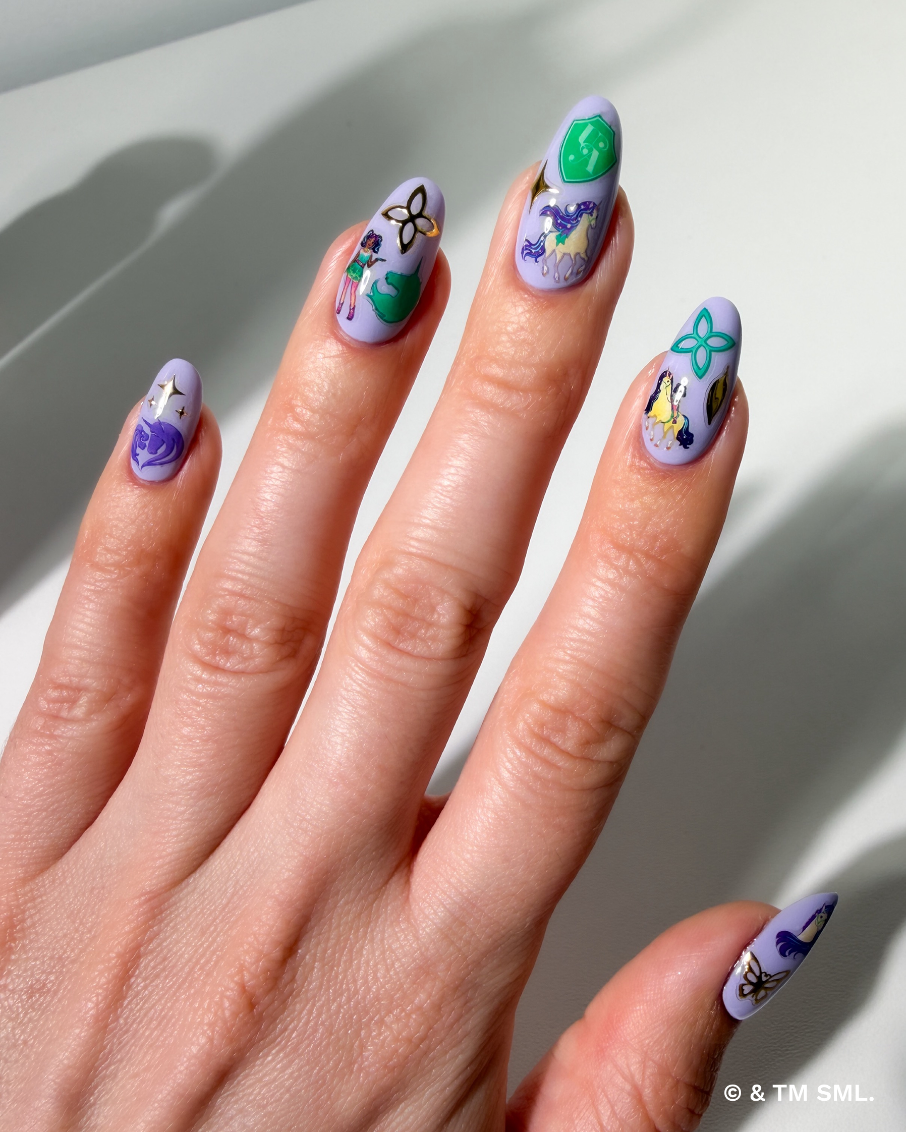 Hand with cartoon stickers on purple nails on a neutral background