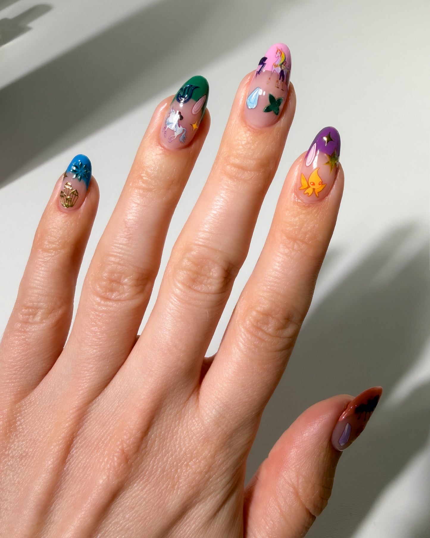Hand with colorful nail art stickers on a neutral background