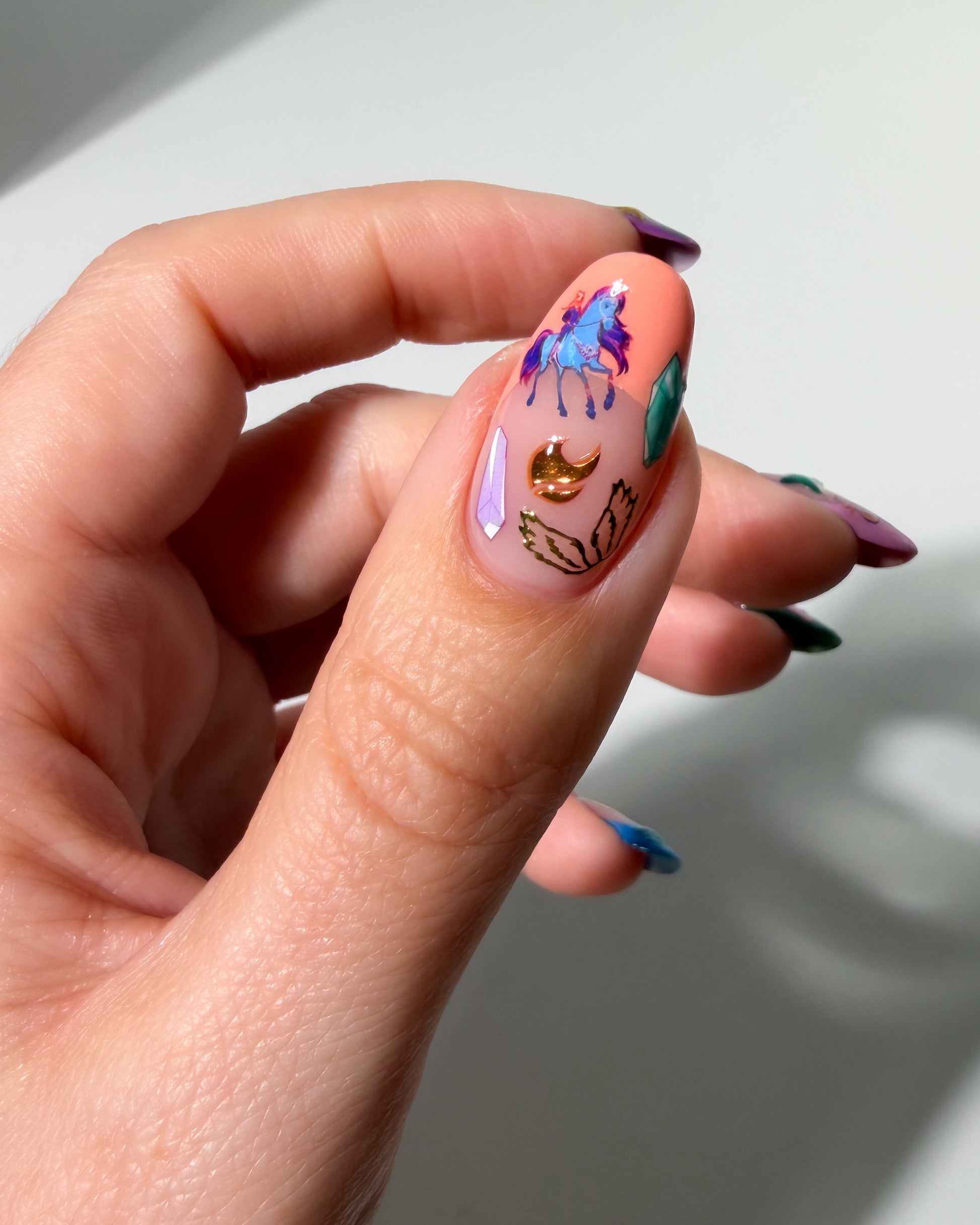 Thumb with colorful nail art stickers.