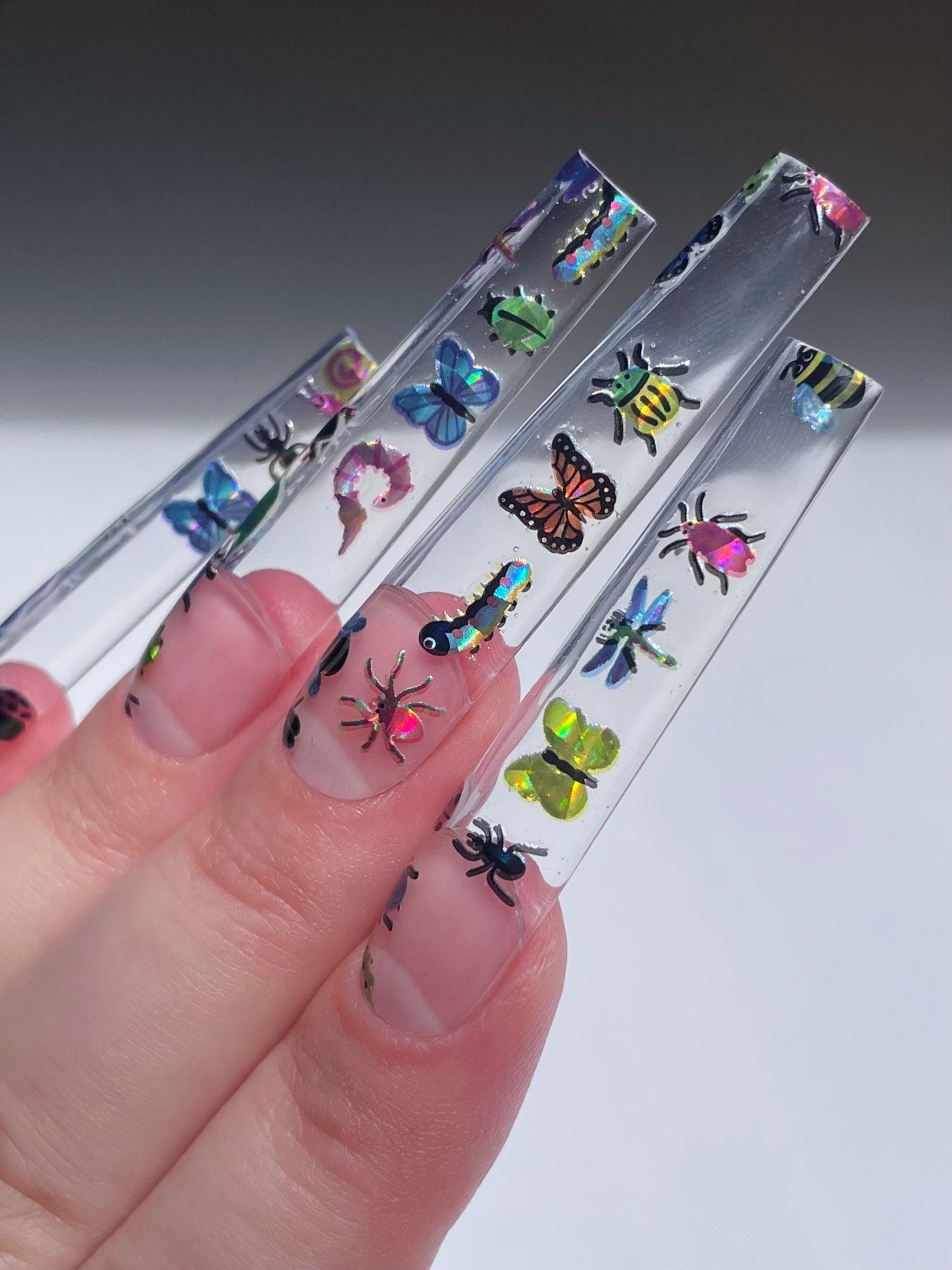 Long clear nail extensions with holo bug stickers