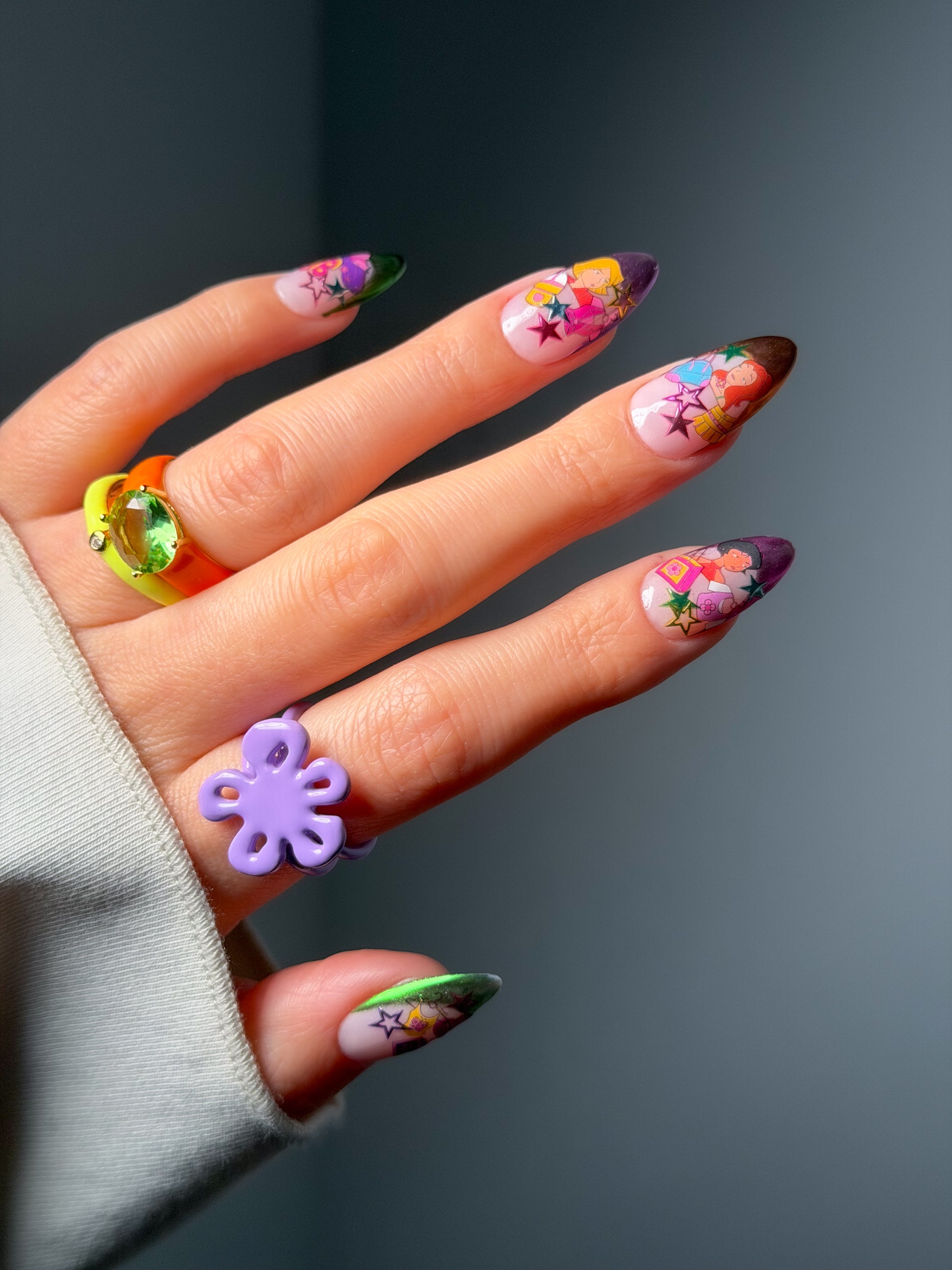 Hand with colorful floral nail art stickers on a dark background