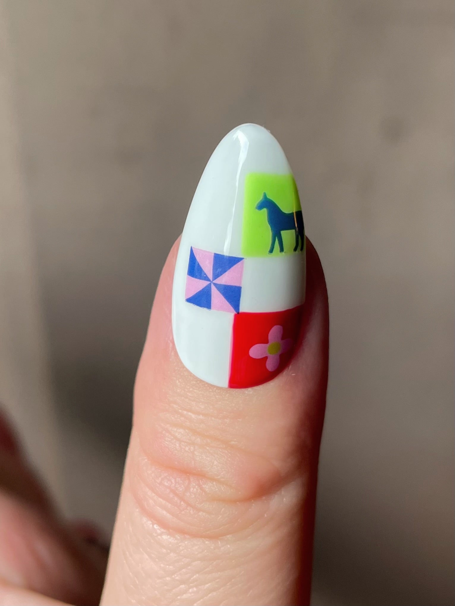 Close up of a thumb nail with a white base and stickers from the Pinwheel nail art sheet