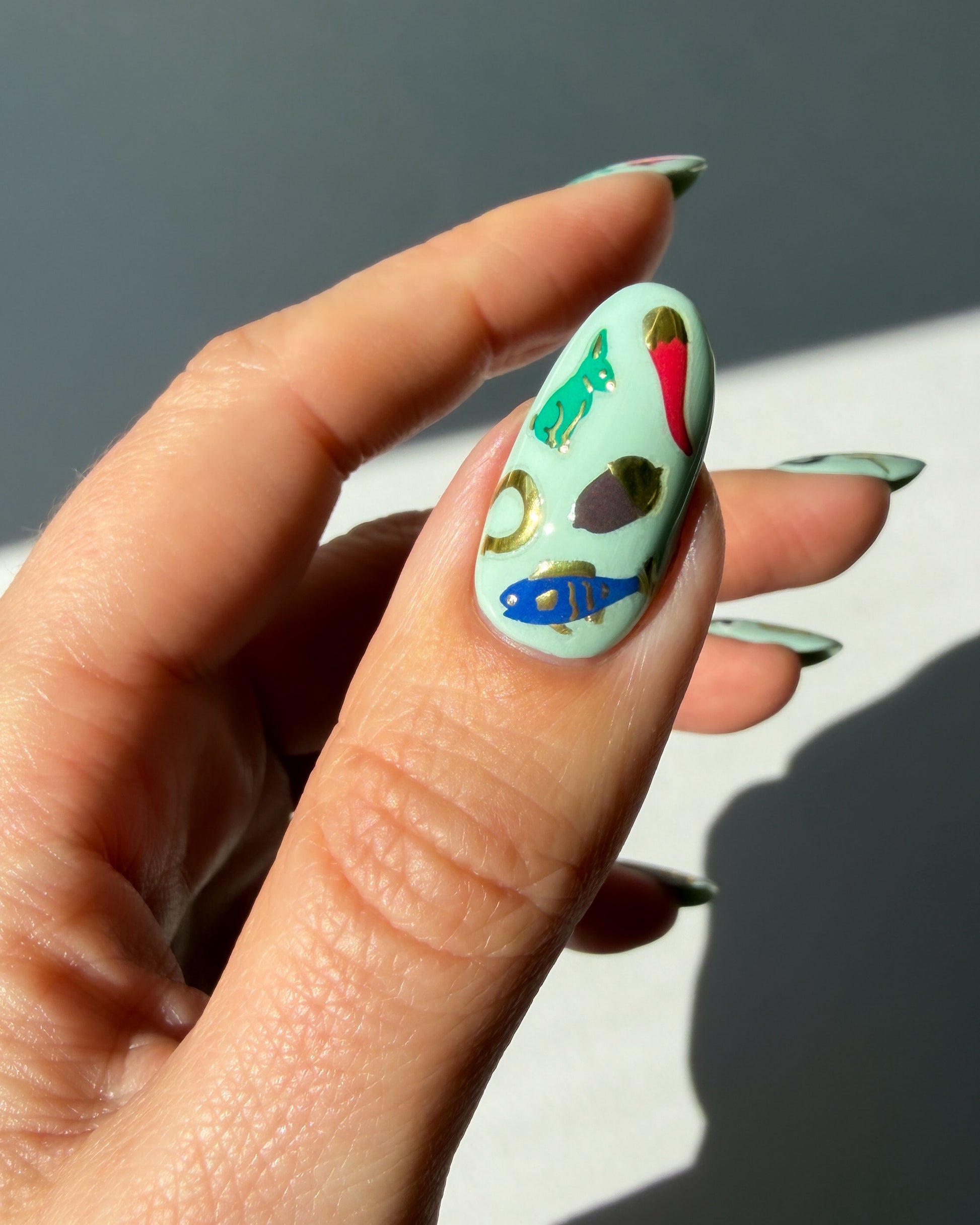 Good Fortune nail art stickers on a minty thumb nail