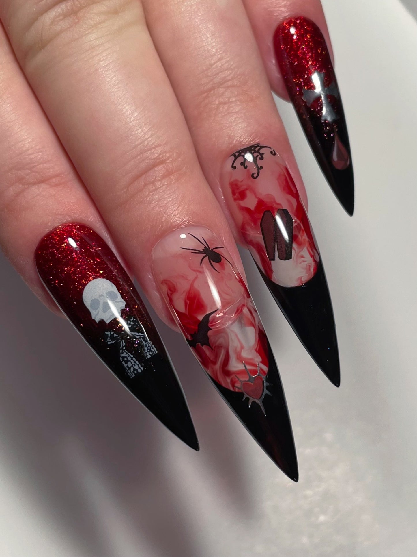 Close up of long stiletto nails with black French, red glitter, and stickers from the Vamp nail art sheet