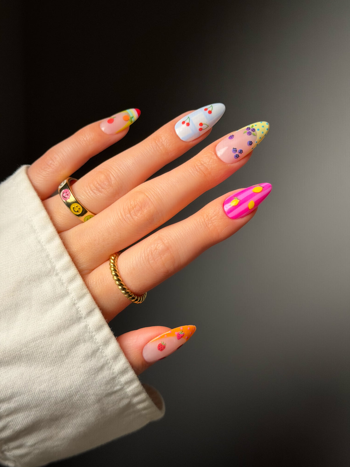 Hand with colorful nail polish and tiny fruit stickers