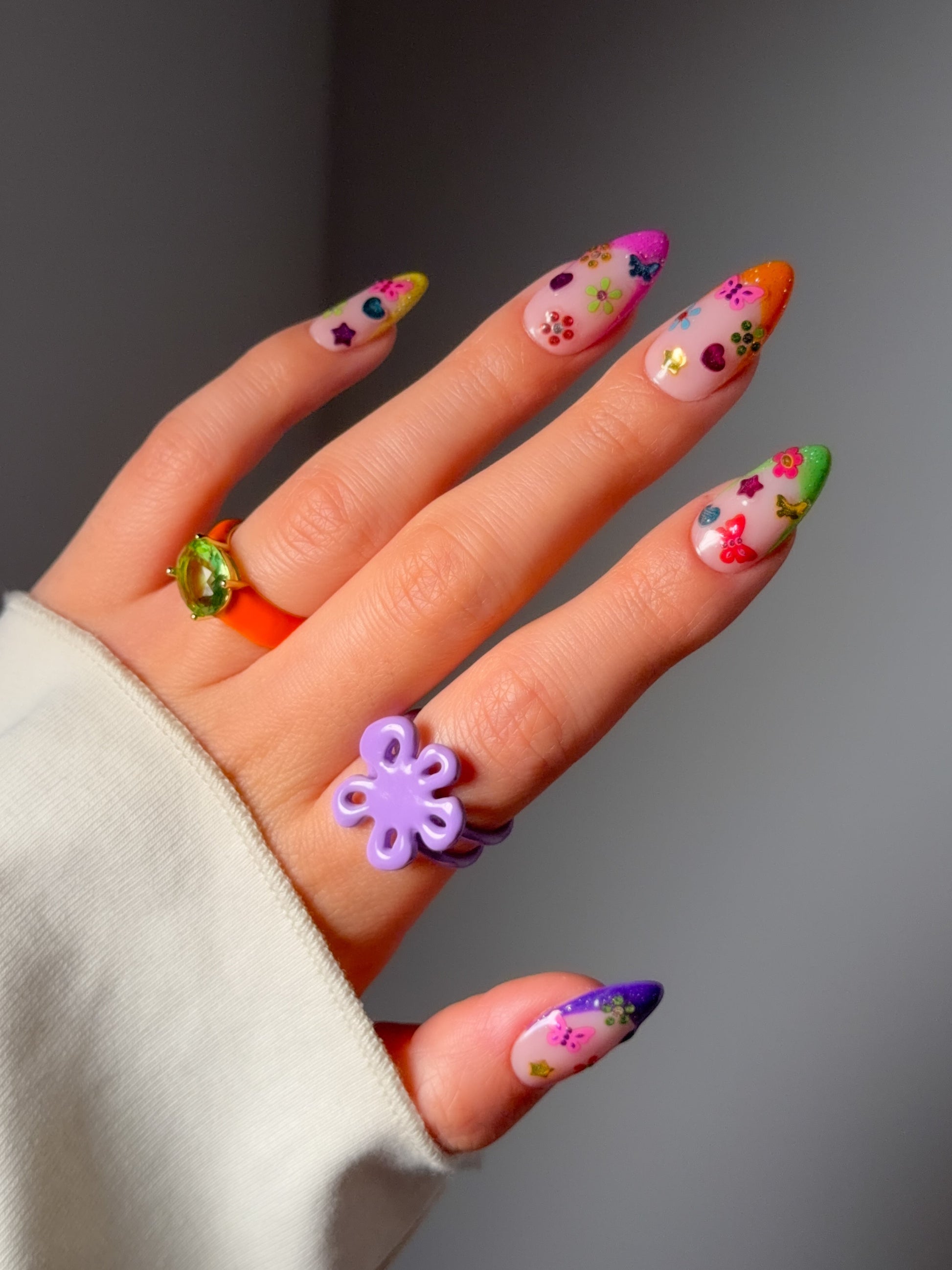 Hand with colorful nail art stickers on a neutral background