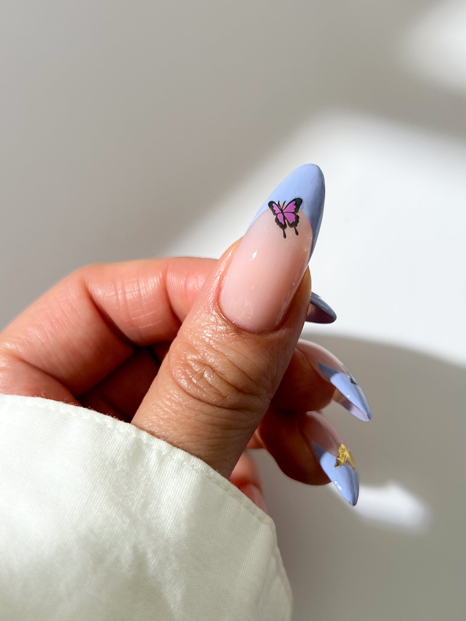 Nail with butterfly sticker against a neutral background