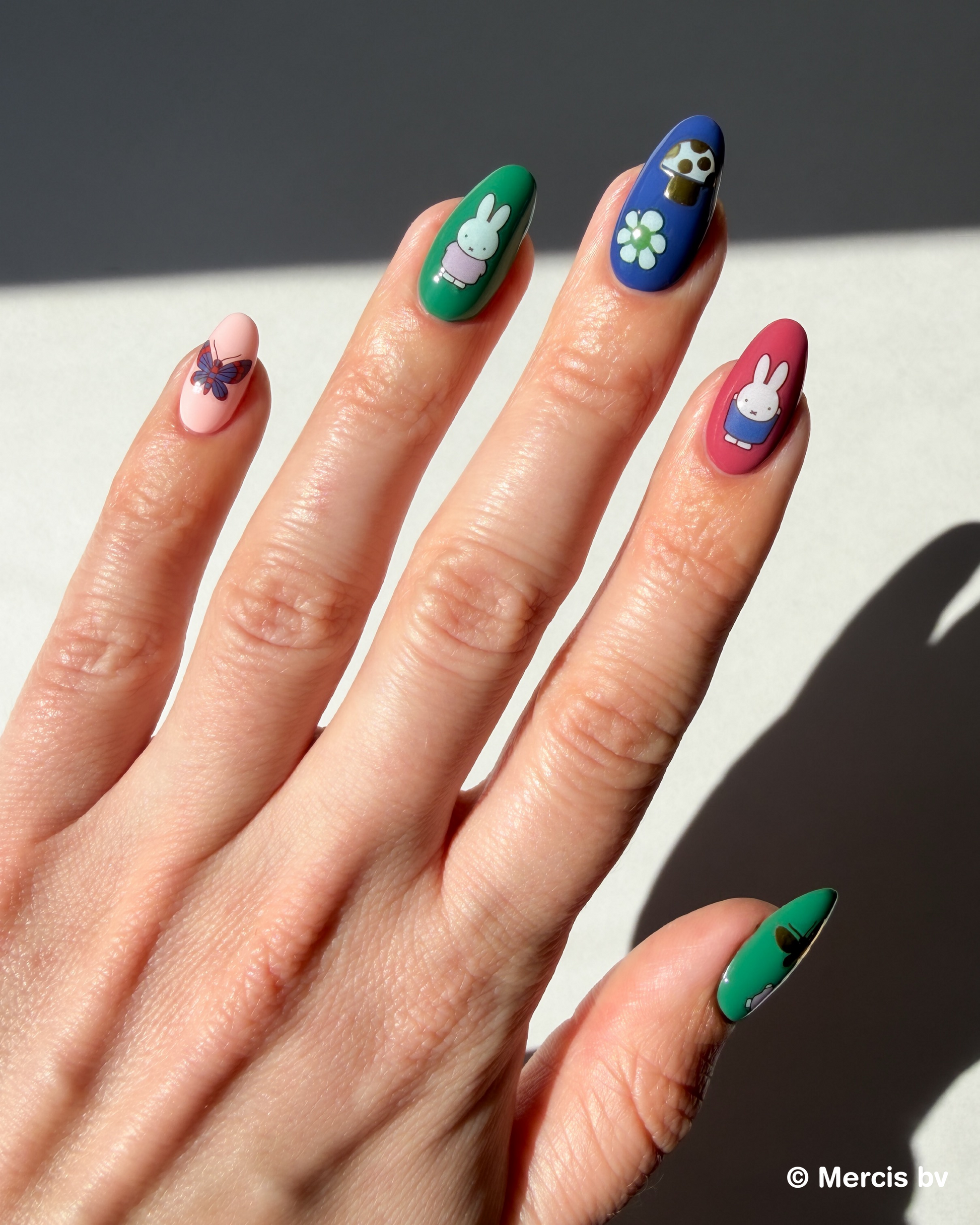 Hand with colorful nails and Miffy stickers on a neutral background