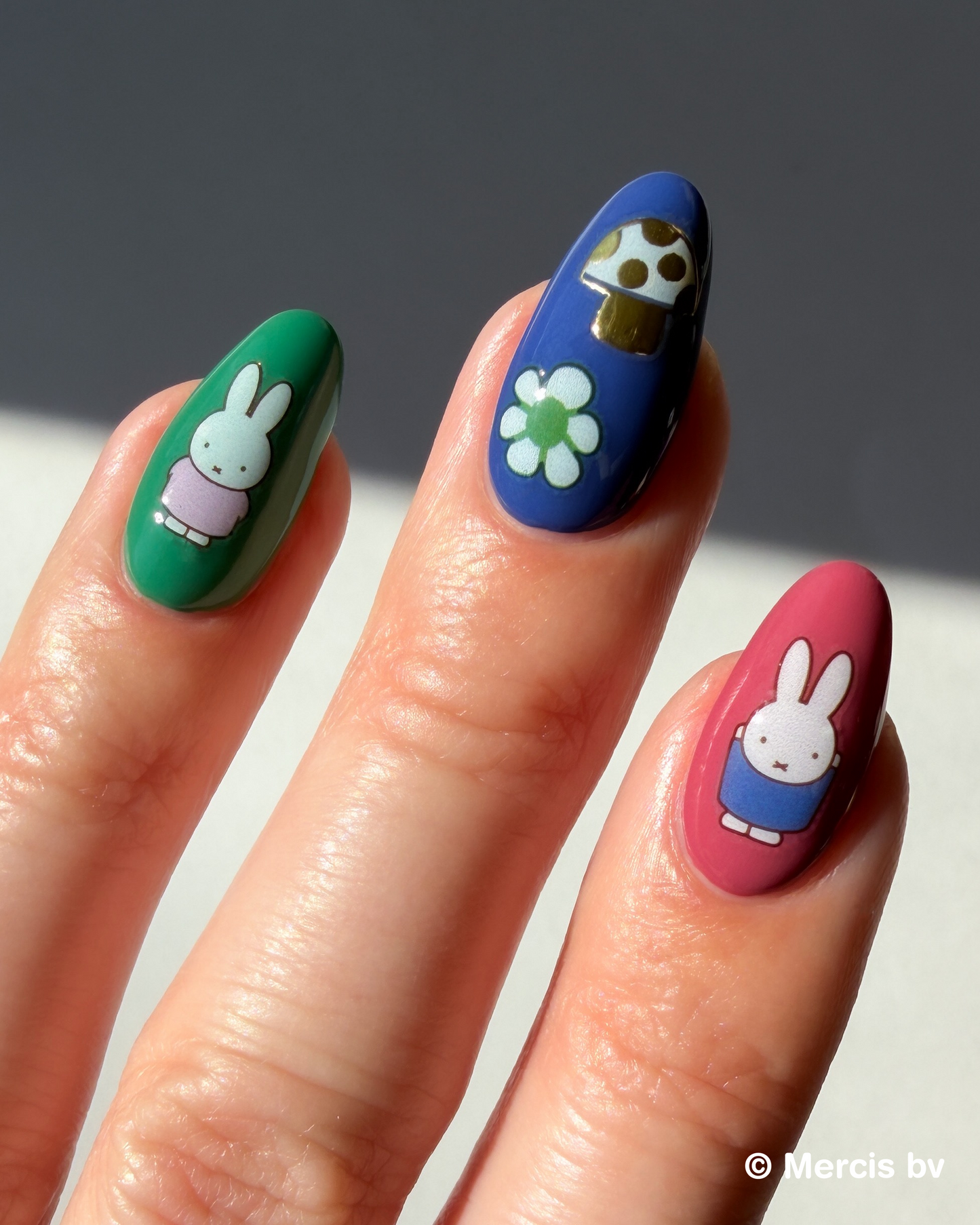 Hand with colorful nails and Miffy stickers on a neutral background
