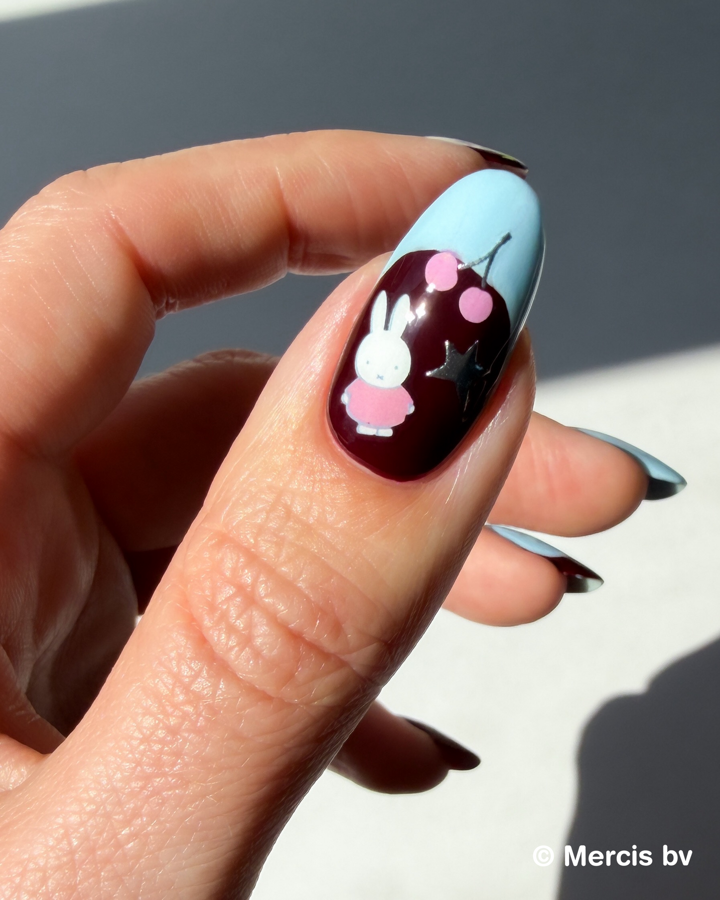 Nail art Miffy stickers on a dark base with blue French tip.