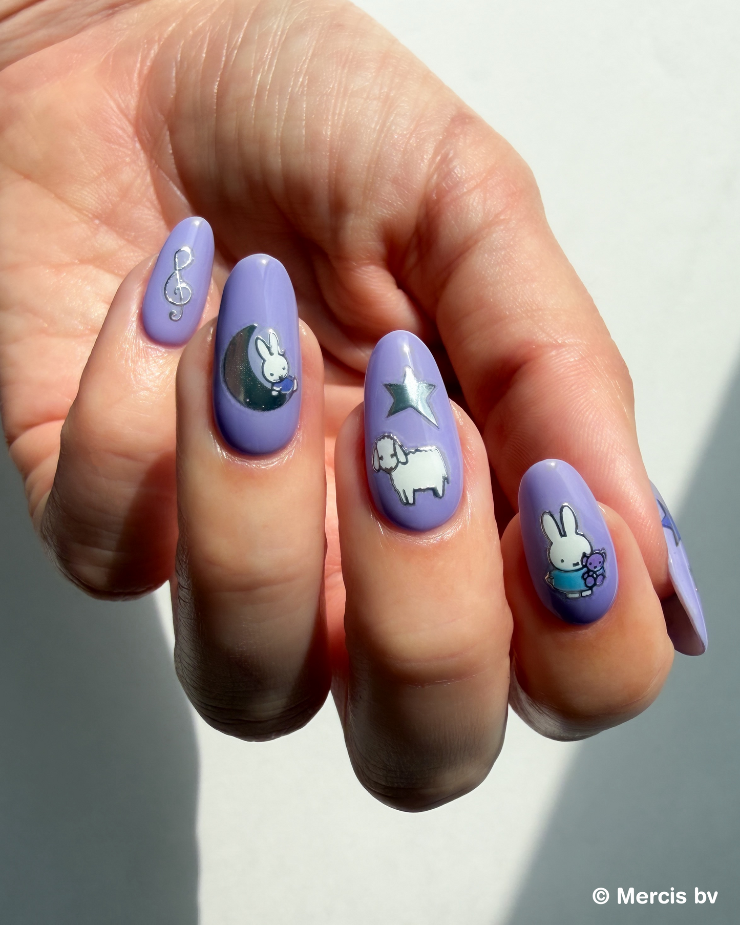 Hand with purple nail polish and Miffy stickers on a light background