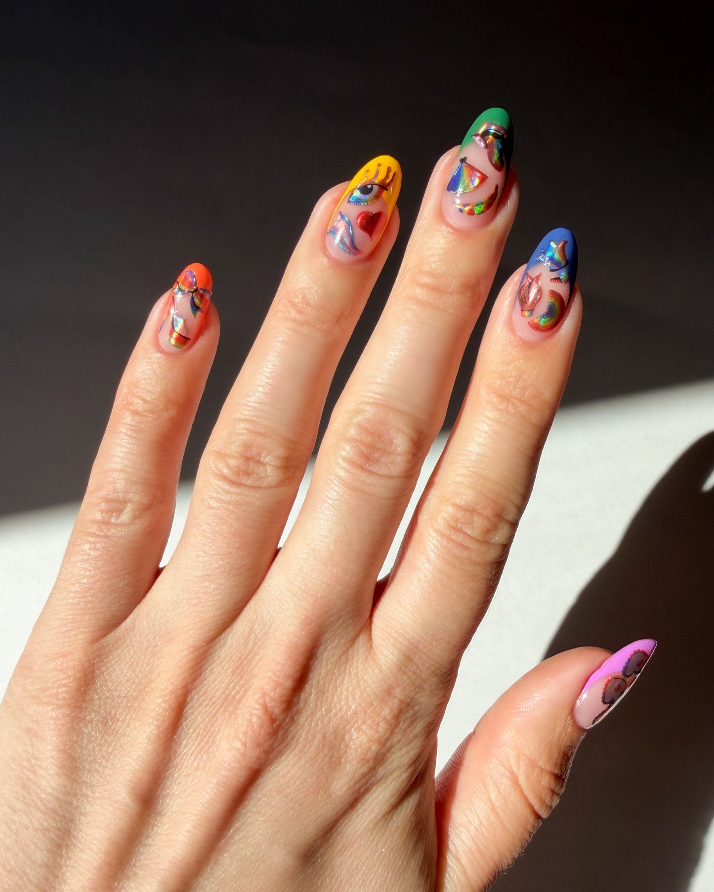 Hand with colorful nail art on a dark background