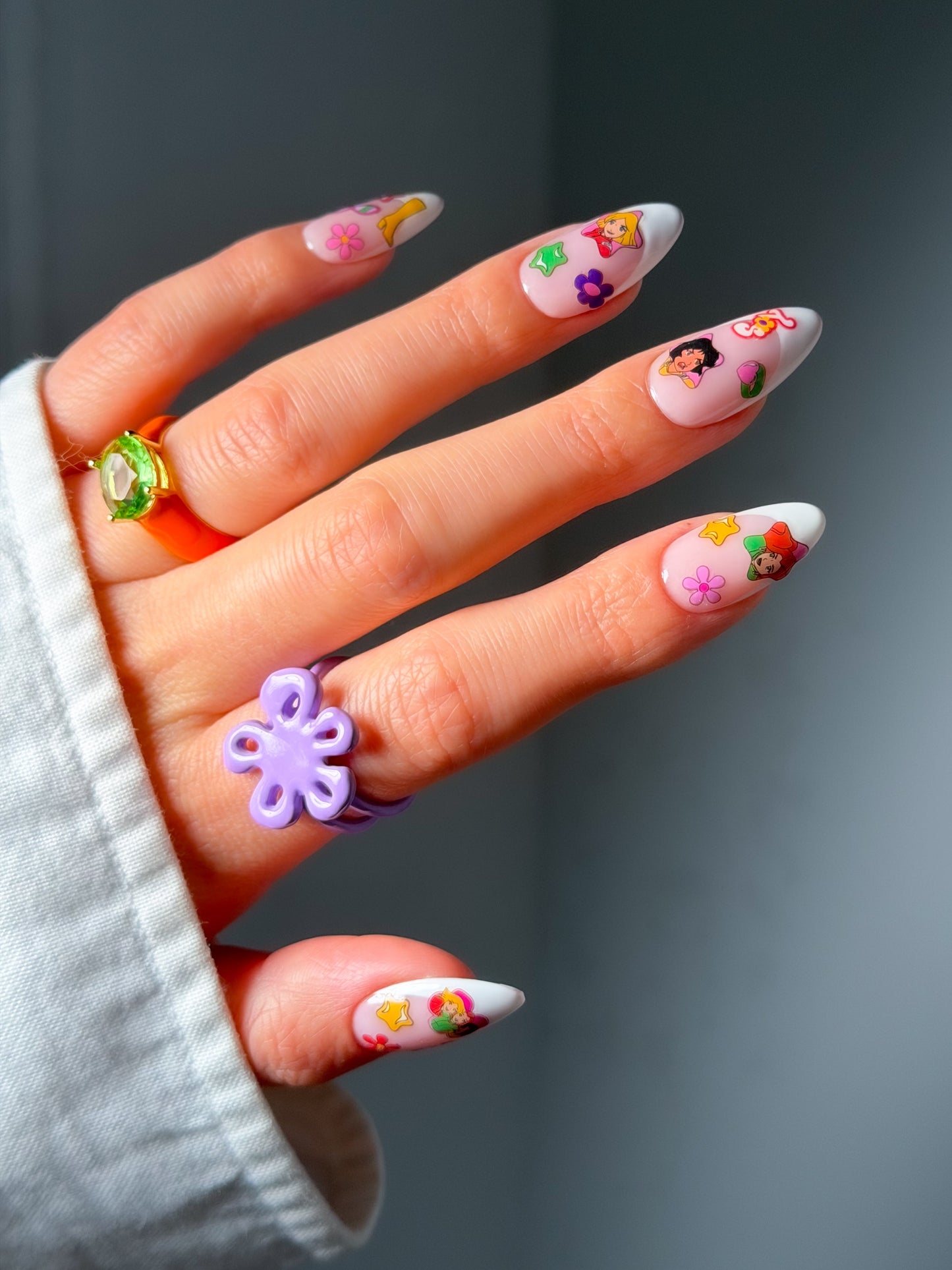 Hand with colorful nail art stickers on a gray background