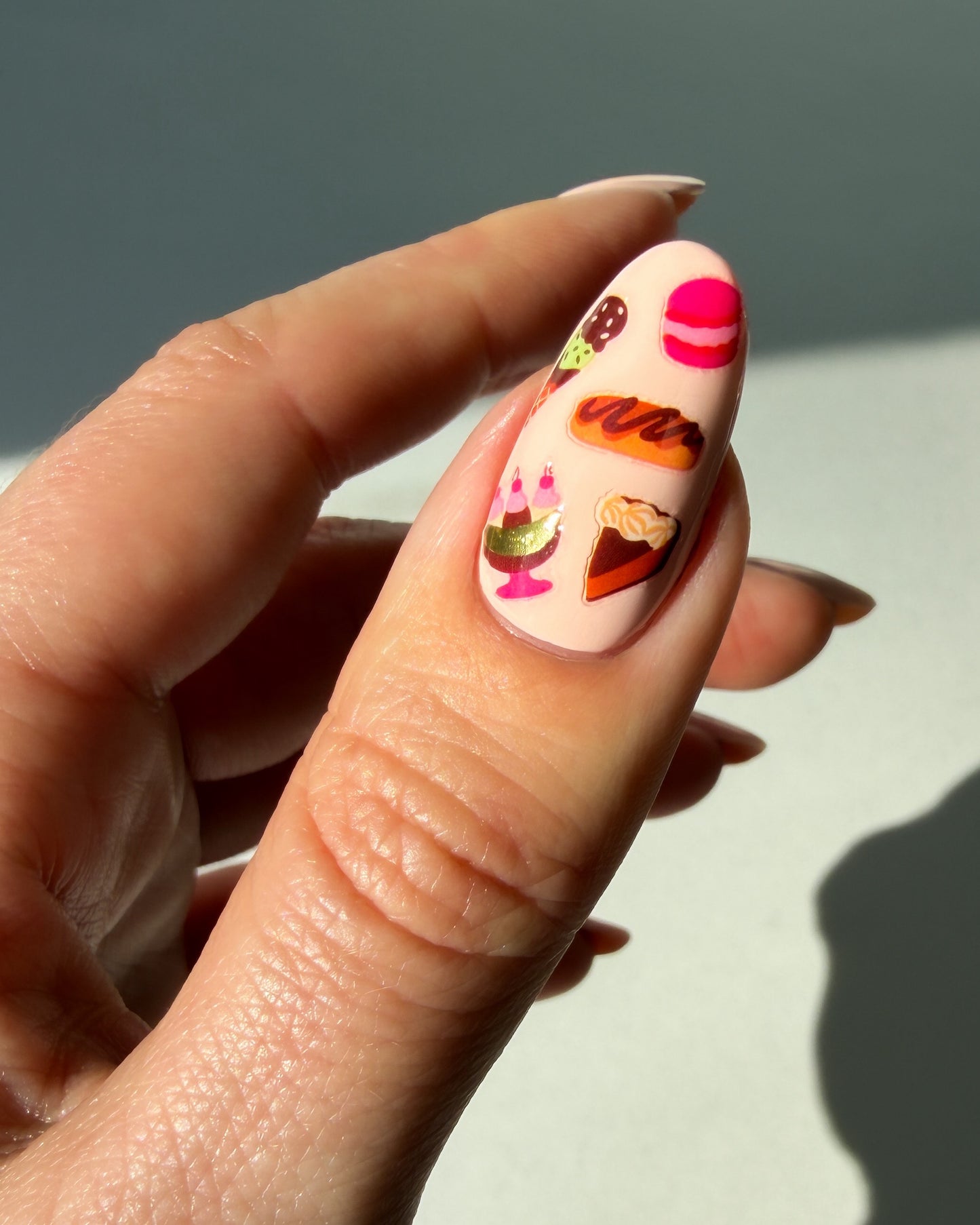 Dessert nail art stickers on a peachy thumb nail