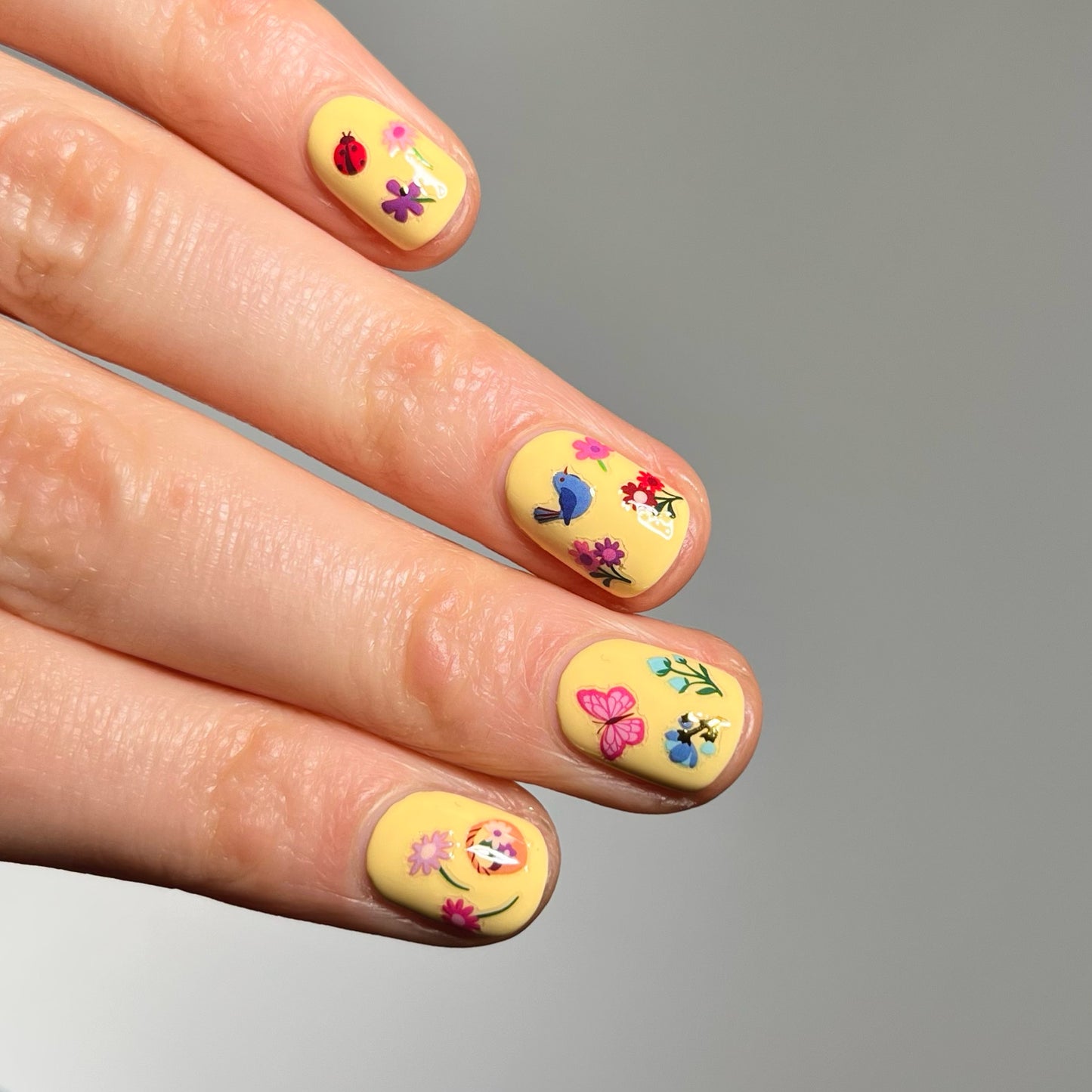 Hand with yellow nail polish and tiny flower stickers