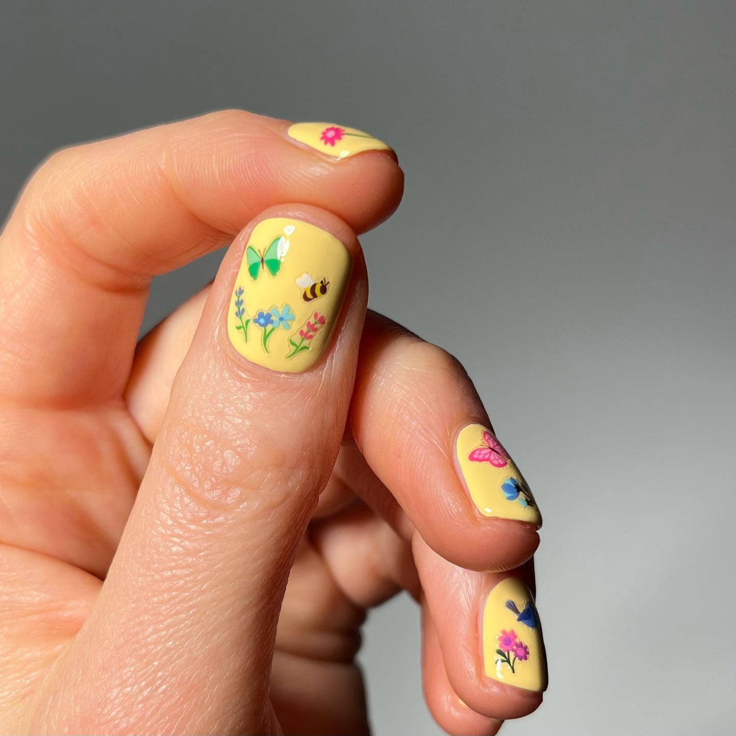 Hand with yellow nails polish and tiny flower stickers
