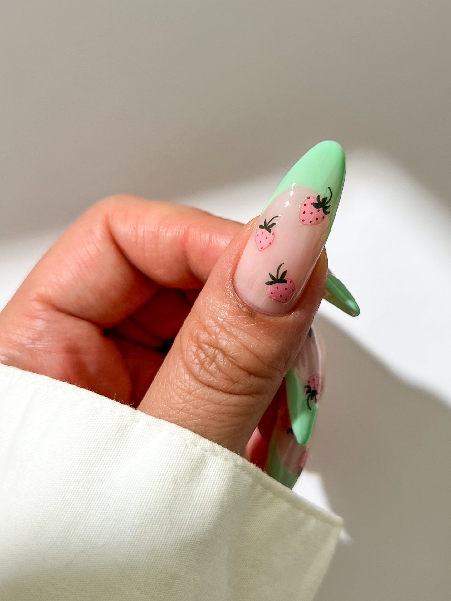 Nail with green french nails and pink strawberry stickers