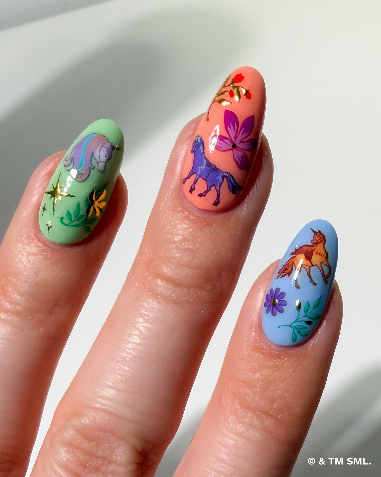 Nails with colorful designs of a horse, fox, and elephant on a light background