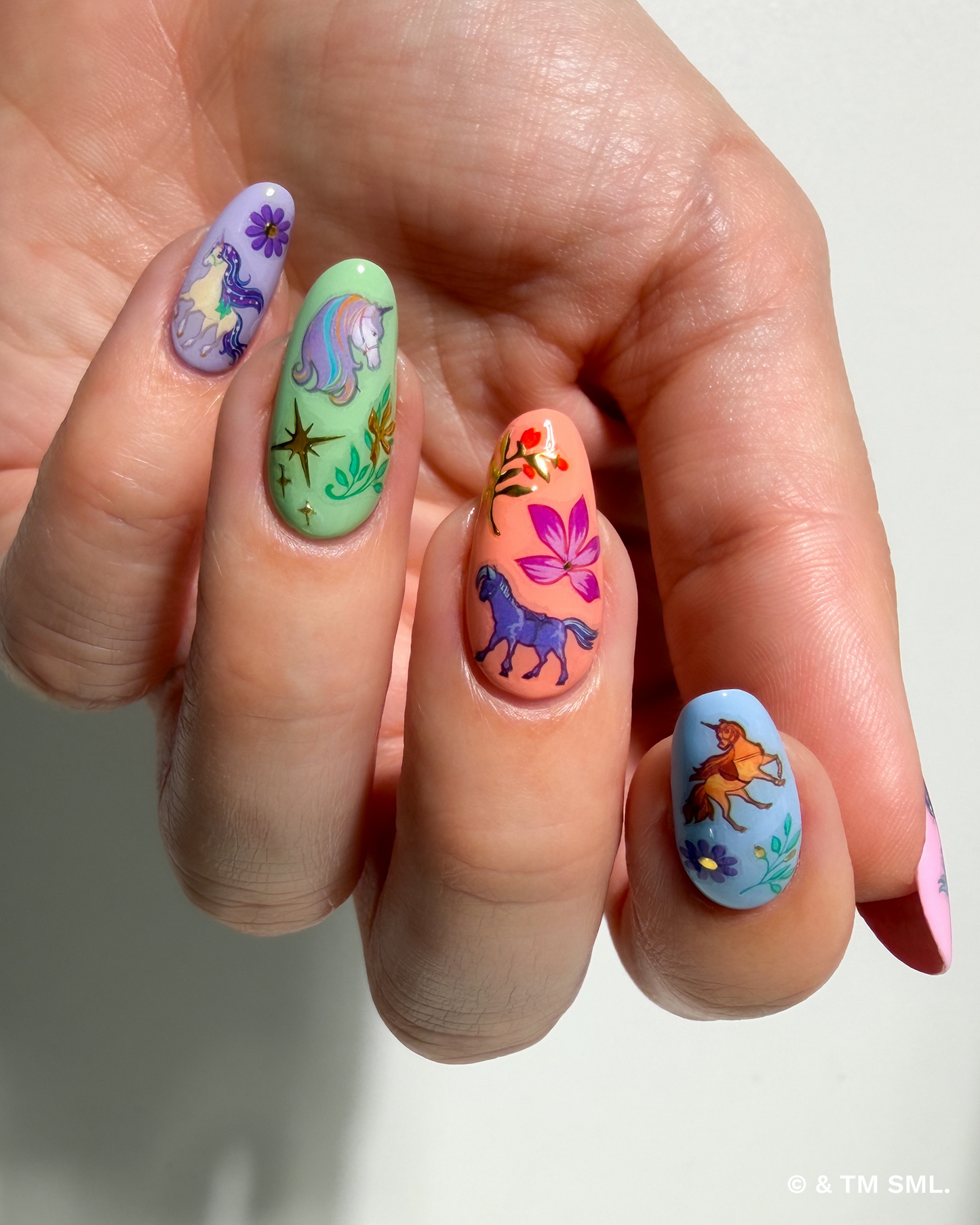 Hand with colorful nail art featuring animals and flowers on a white background