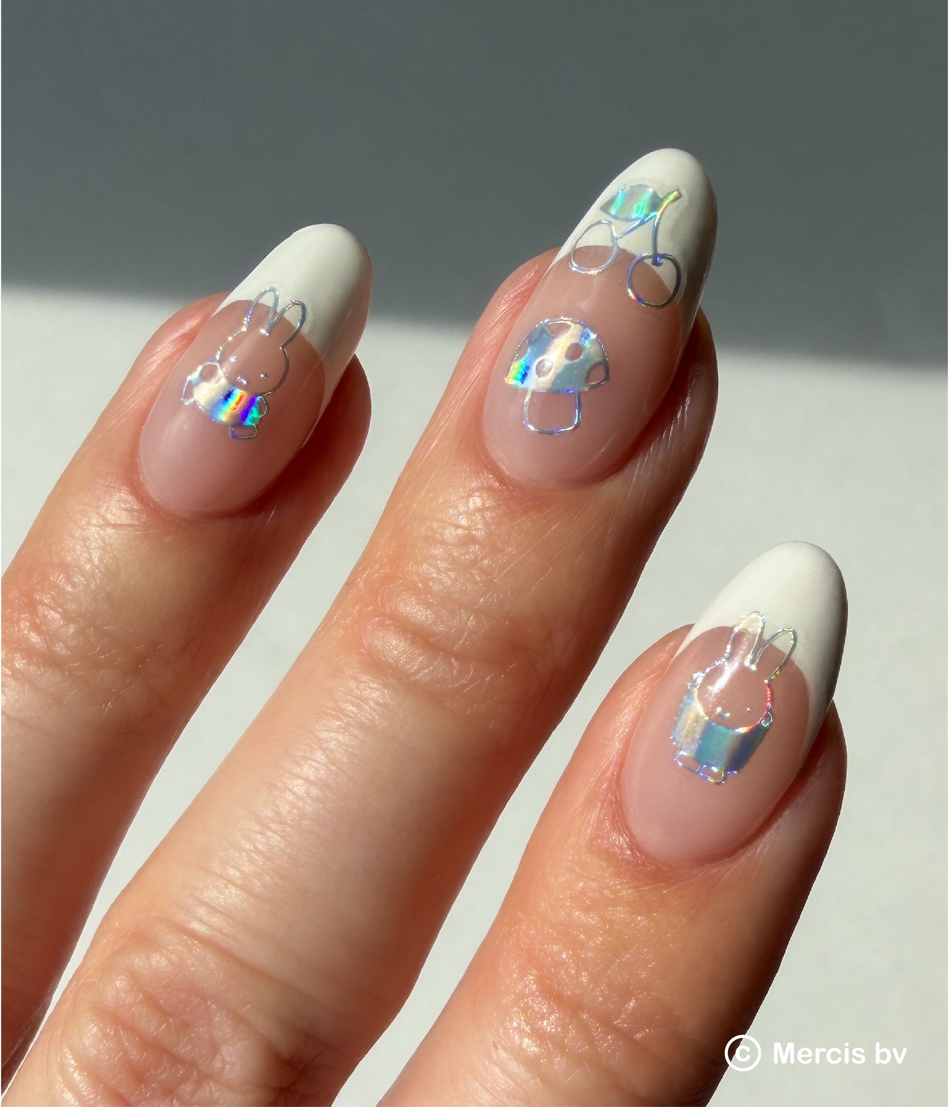 Nails with holo Miffy and teddy bear nail art stickers on a neutral background