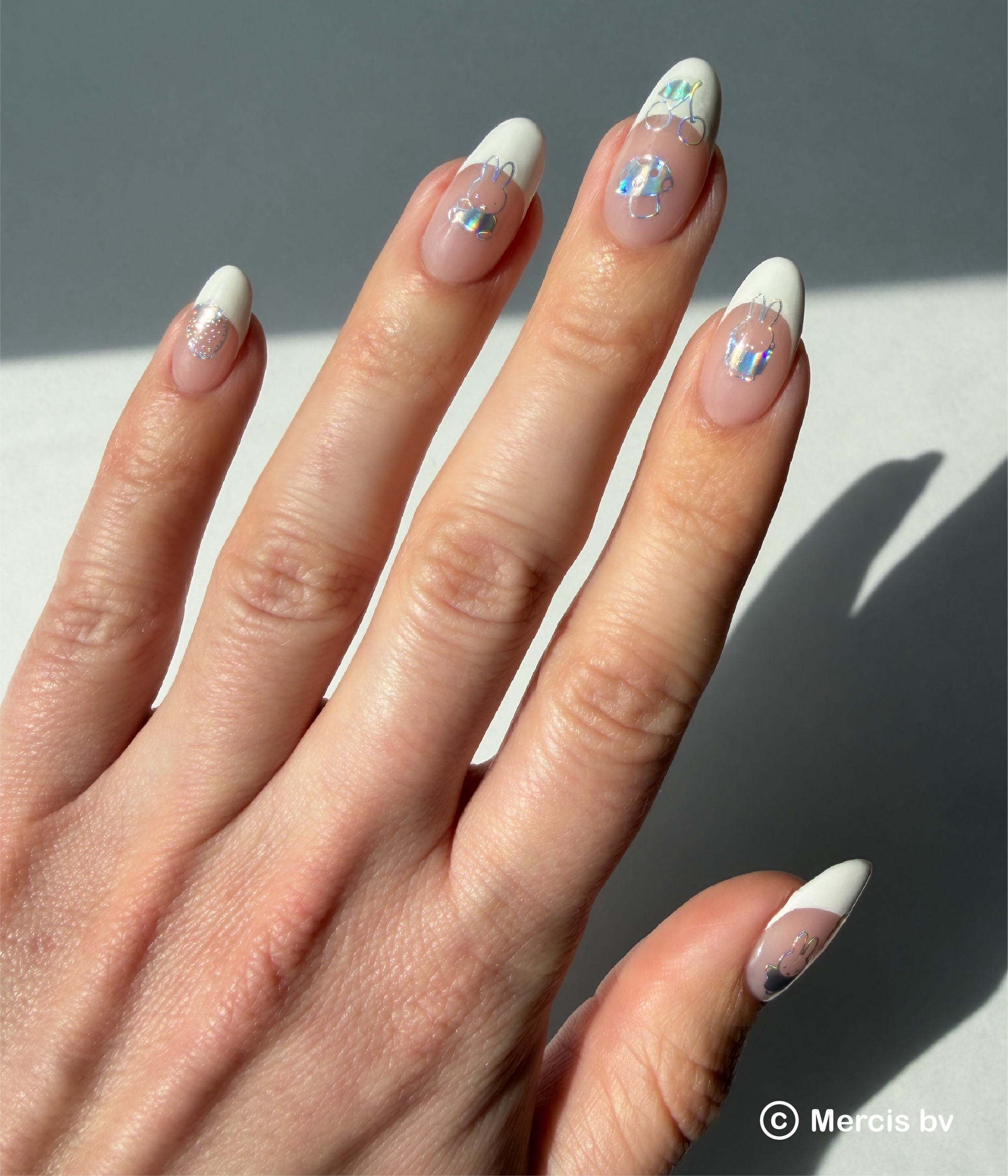 Hand with holo nail art stickers on a neutral background