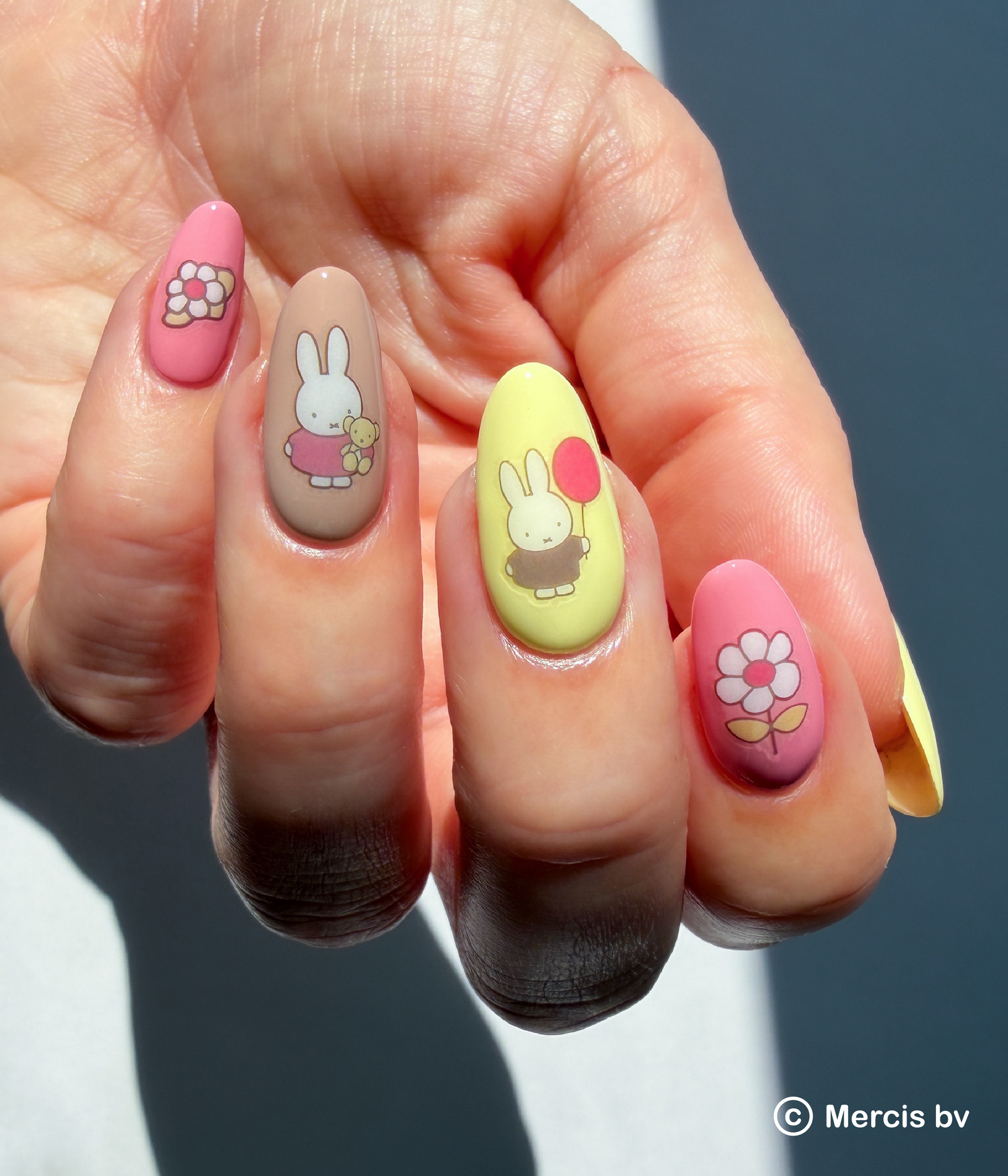 Hand with colorful polish and Miffy and floral nail art stickers